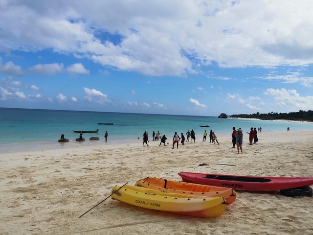       People enjoying a beach with kayaks and boats.
  