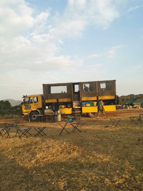       Large yellow truck used for overland travel with people nearby.
  