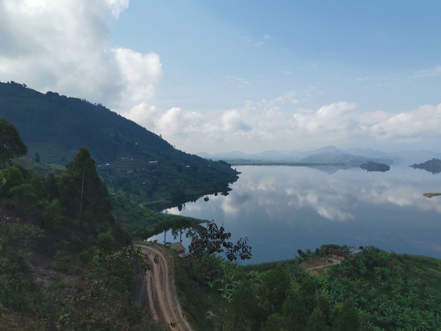 Lakeside view with mountains and cloudy skies.