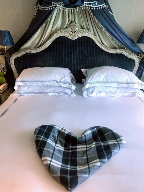 Hotel bed with pillows and a person's feet visible at the bottom.