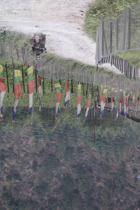 Motorcycle on a dirt road lined with colorful flags.