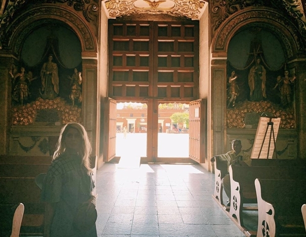 Interior of a church with a view through the open doors to the street.