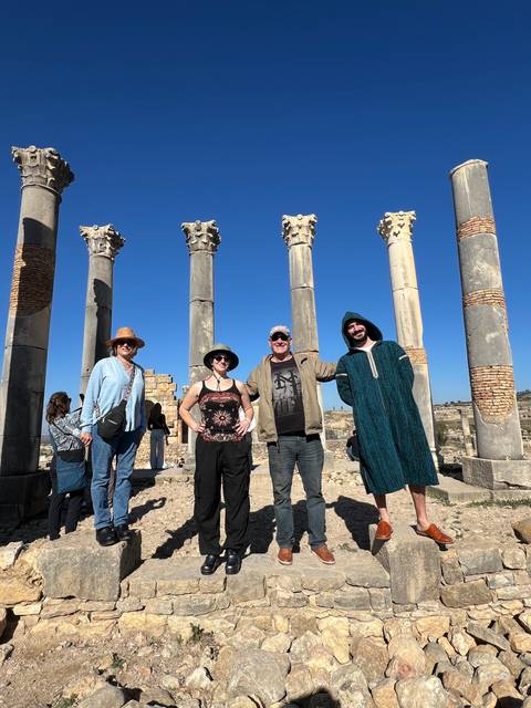 Group of people standing near ancient ruins with columns.