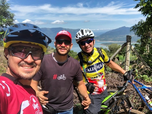 Three cyclists with a mountainous landscape in the background.