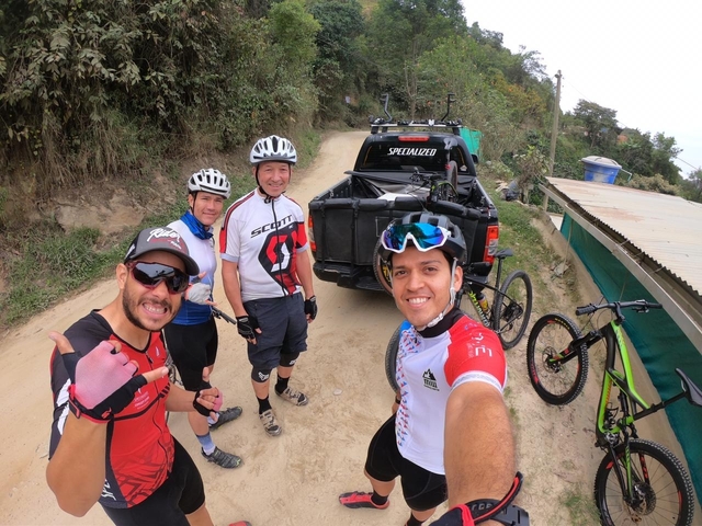 Group of cyclists near a vehicle on a dirt road.