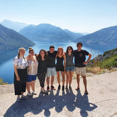 Group of people posing with a lake and mountains in the background.