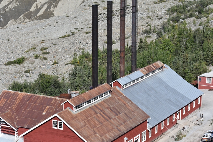      Red industrial buildings with a mountainous backdrop.
  
