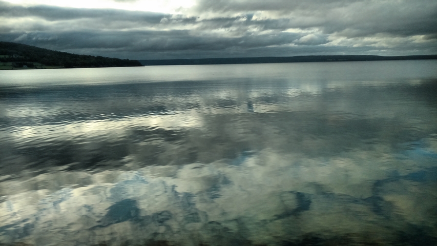       Moody view of a lake with cloud reflections.
  