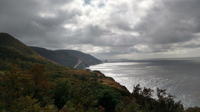       Scenic coastal road with ocean and hills.
  