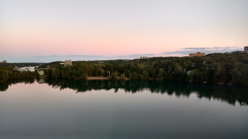       Lake view with buildings in the distance at sunset.
  