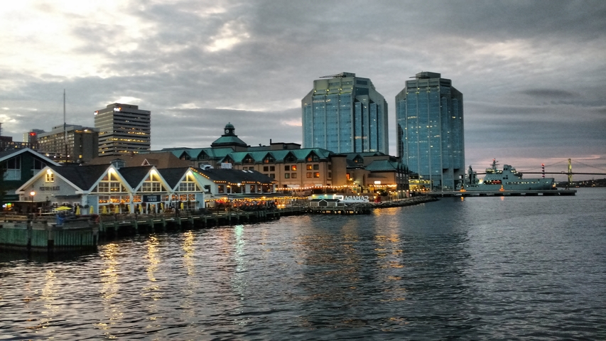       Harbor at dusk with city skyline reflecting in water.
  