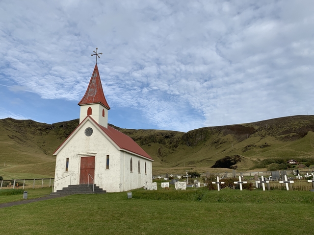 Quaint church with a red roof in a valley landscape.