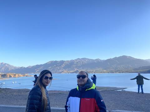 Mountains viewed across a body of water with a couple posing in the foreground.