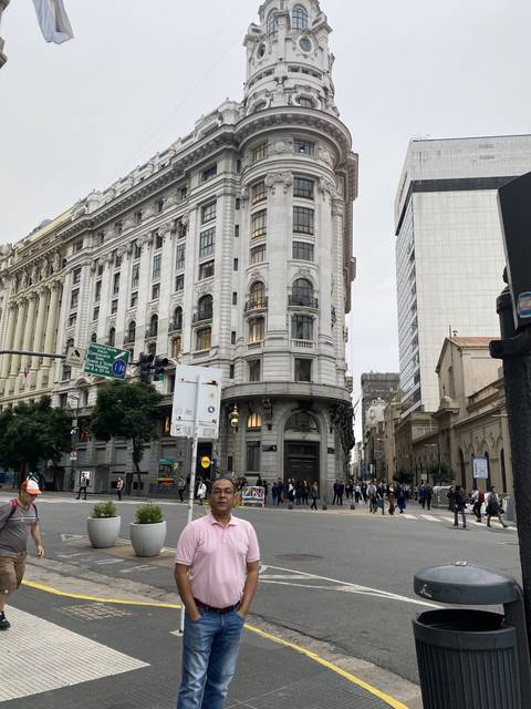 A man on a street next to a tall, historic building.