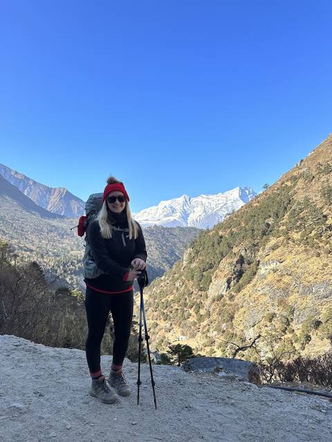       Hiker with trekking poles on a mountain trail.
  