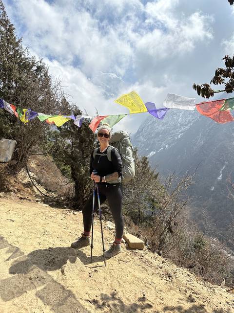       Hiker on a trail with prayer flags fluttering.
  