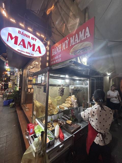 Person preparing street food at a vendor's stall.