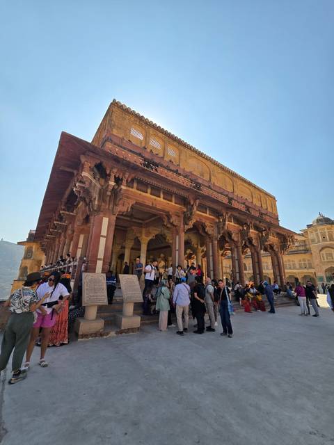 Crowd gathered at a historical entrance with red sandstone.