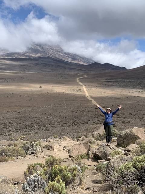       Person posing on a mountain trail with expansive views.
  
