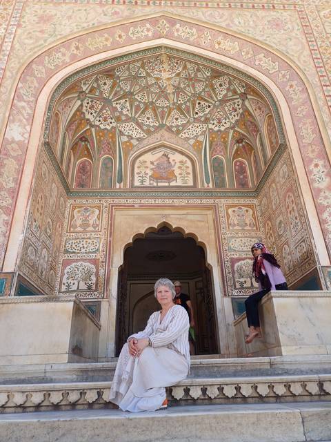 Person sitting in a decorated entrance of a fort with intricate designs.