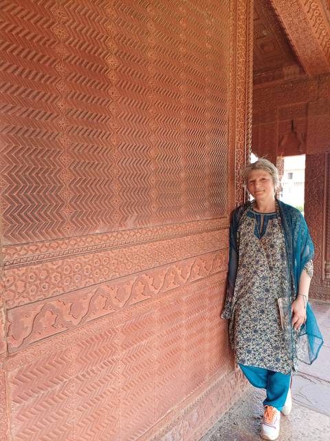 Person leaning against a wall with intricate carvings.