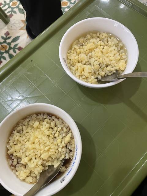 Bowls of rice with toppings on a green tray.