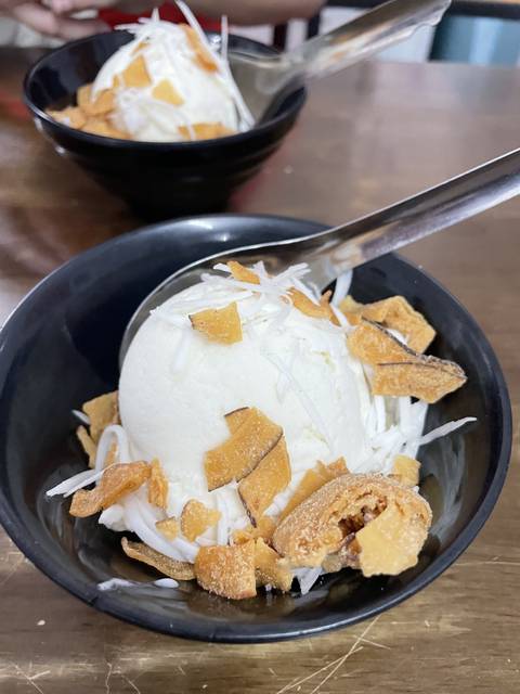 Scoops of ice cream with toppings in bowls.