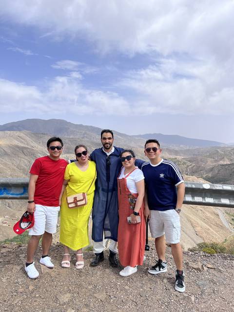       Group of people posing with mountains in the background.
  