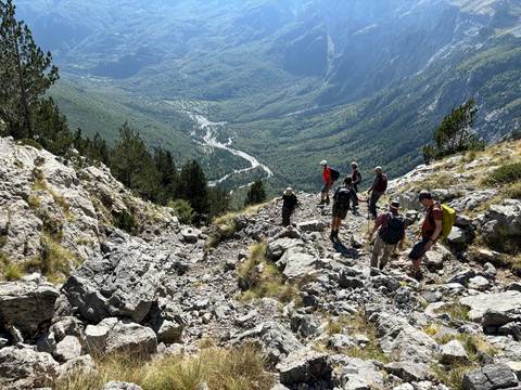 Hikers walking along a steep trail with a cliff view.