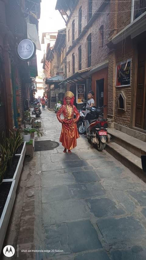       Traditional dressed girl walking down a street lined with shops.
  