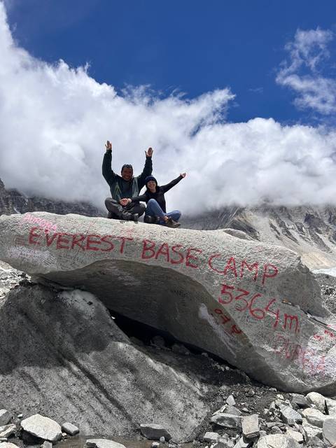 Group of people posing on a rock labeled Everest Base Camp