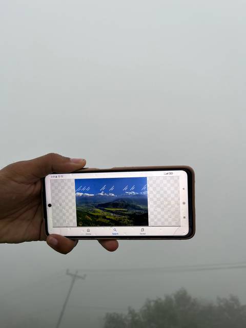       Hand holding a smartphone showing a photo of mountains.
  