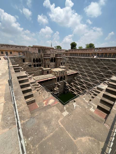 Stone step-well with intricate design and clear blue sky.