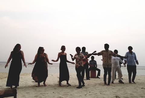       Group of people dancing on a beach.
  