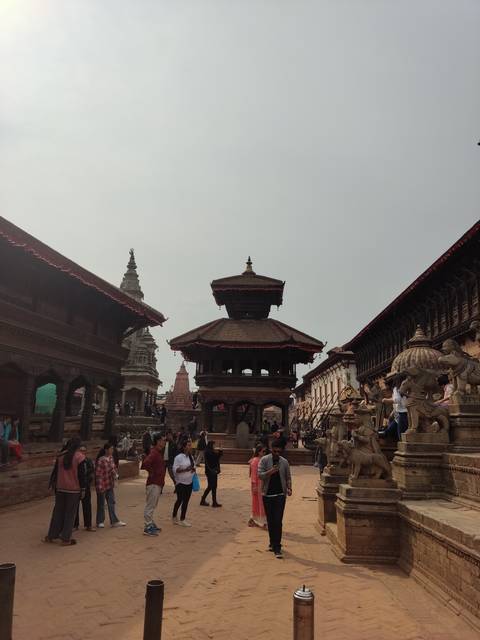       Busy square with traditional architecture and people walking.
  