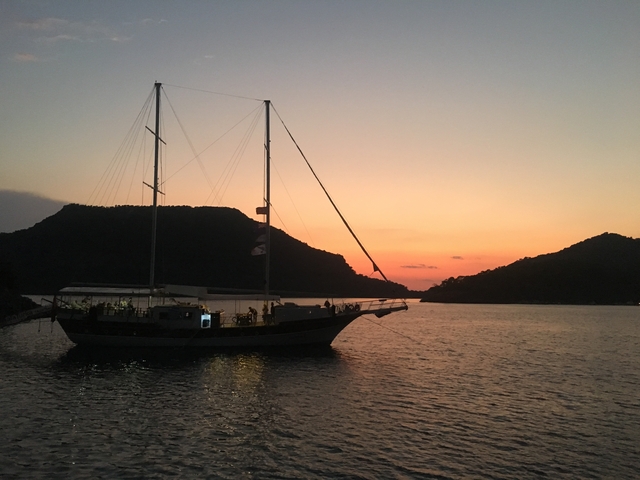 Sailboat anchored in a bay at sunset.