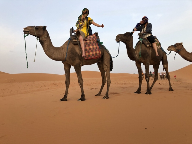 People riding camels in the desert.