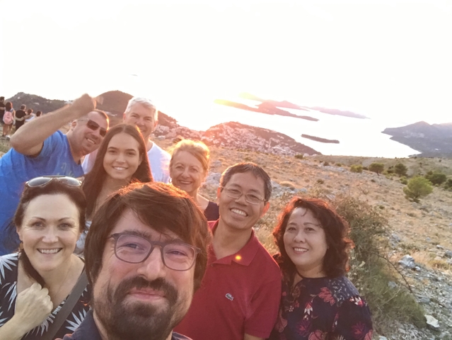       Group selfie with a scenic sunset background.
  