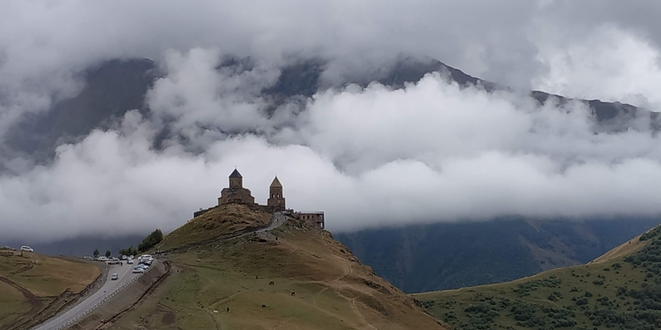 Iconic church on a hilltop surrounded by fog and mountains.