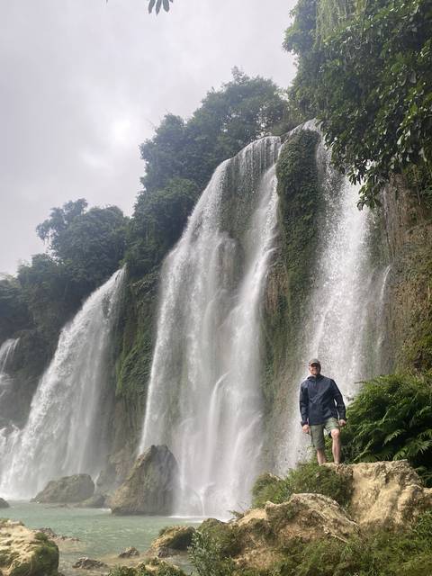       Person standing by a large waterfall.
  