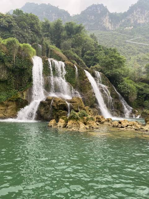       Waterfall flowing into a clear green pool.
  