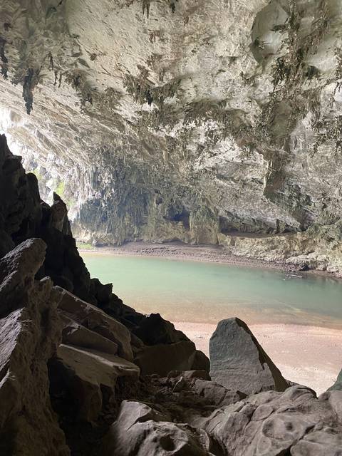       Cave with a rocky interior and a body of water.
  