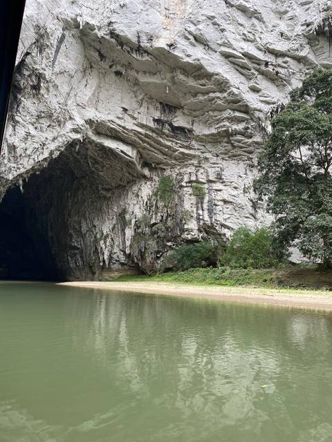       Tall rocky cliff beside a calm river.
  