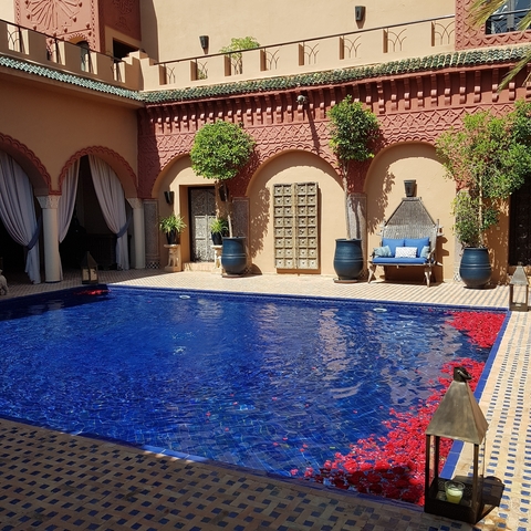       Blue pool in a traditional courtyard with architectural details.
  
