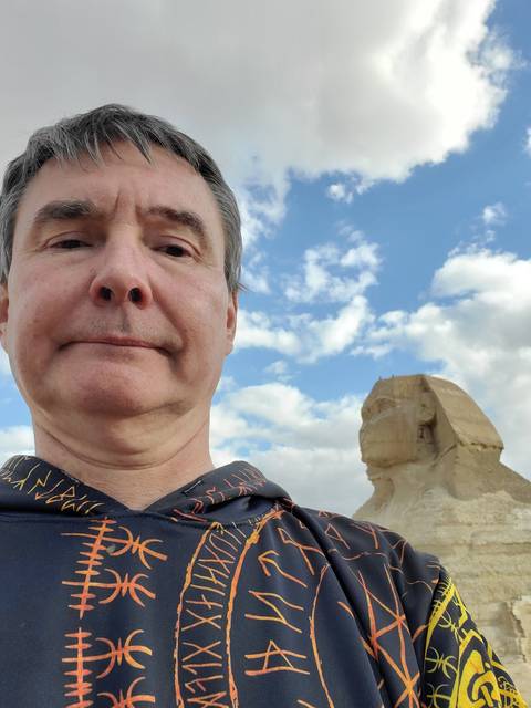       A man with a partial view of a large stone monument in the background.
  