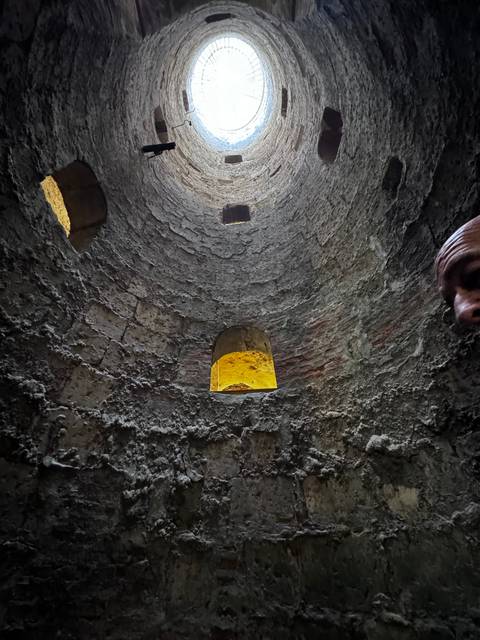       Interior of a stone tunnel with light at the end.
  