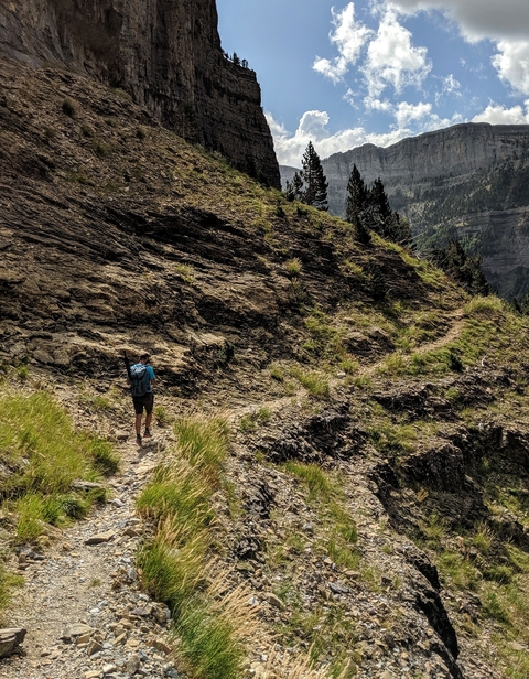 A person hiking along a rocky trail in a mountainous landscape.