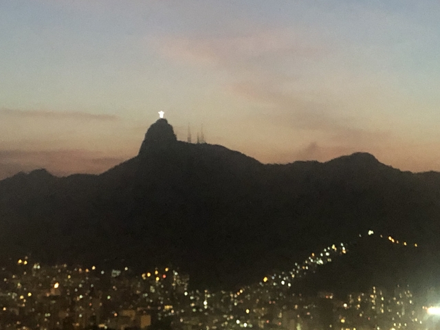 Distant view of a hill with a statue lit in the evening.