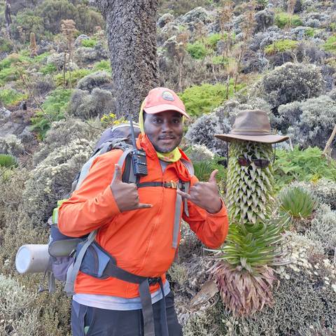       A person posing with hiking gear and radio in a hilly landscape.
  