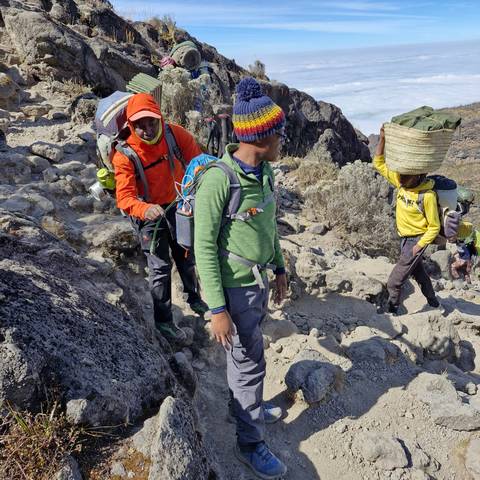       Hikers ascending a rocky path in a mountainous region.
  